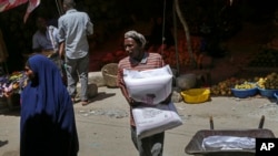 FILE - A man carries a sack of wheat flour imported from Turkey in the Hamar-Weyne market in Mogadishu, Somalia, May 26, 2022. Families across Africa are paying about 45% more for wheat flour as Russia's war in Ukraine blocks exports from the Black Sea.