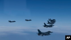FILE - In this photo provided by South Korea Defense Ministry, U.S. and South Korea Air Force fighter jets fly in formation during a joint drill, June, 7, 2022. 