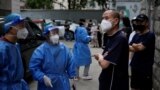 Workers in protective suits direct residents lining up for nucleic acid testing at a residential area, amid new lockdown measures in parts of the city to curb the COVID-19 outbreak in Shanghai, China, June 12, 2022. 