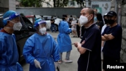 Workers in protective suits direct residents lining up for nucleic acid testing at a residential area, amid new lockdown measures in parts of the city to curb the COVID-19 outbreak in Shanghai, China, June 12, 2022. 