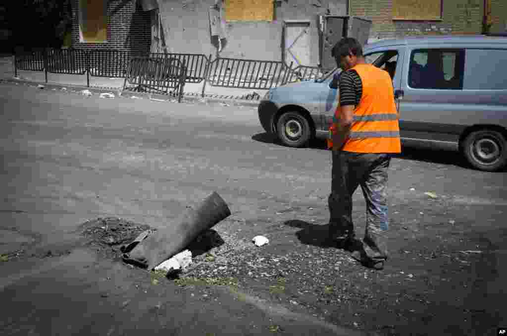 A municipal worker passes by a fragment of a Russian rocket following night shelling in the town of Bakhmut, Donetsk region, Ukraine.