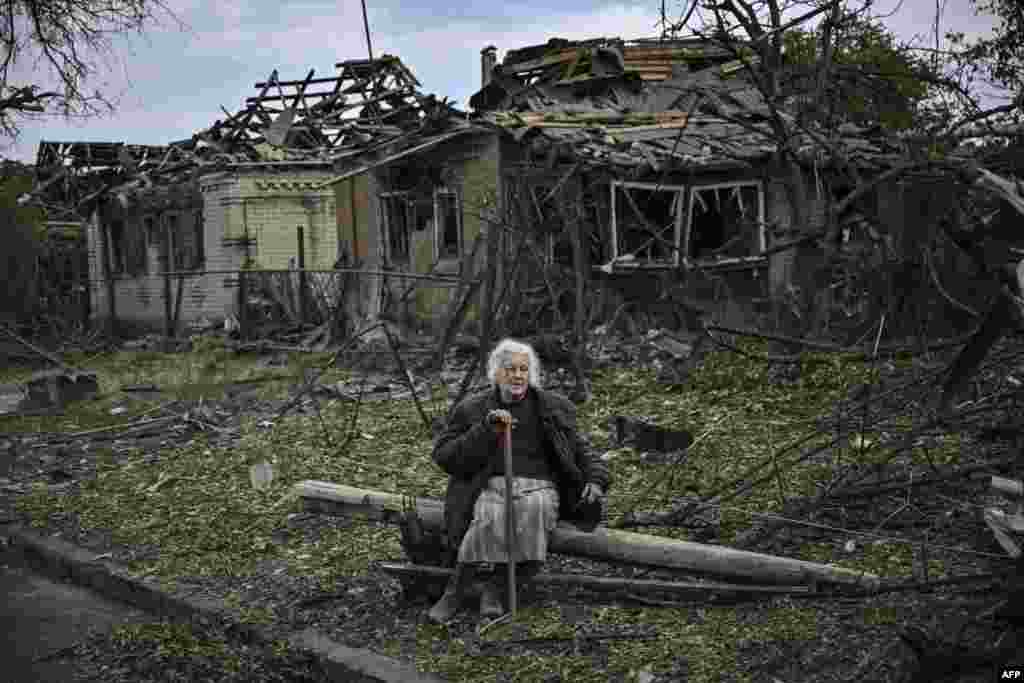 An elderly woman sits in front of destroyed houses after a missile strike in the city of Druzhkivka in the eastern Ukrainian region of Donbas.