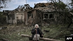 An eldely woman sits in front of destroyed houses after a missile strike, which killed an old woman, in the city of Druzhkivka (also written Druzhkovka) in the eastern Ukrainian region of Donbas, June 5, 2022.