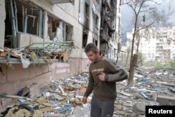 FILE - Local resident Viacheslav walks on debris of a residential building damaged by a military strike, as Russia's attack on Ukraine continues, in Sievierodonetsk, Luhansk region, Ukraine, April 16, 2022.