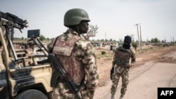 ARCHIVES - Des soldats de la 7e division de l'armée nigériane se tiennent près de la route à Damboa, dans l'État de Borno, au nord-est du Nigeria, le 25 mars 2016.