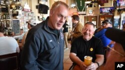 ARCHIVO - El candidato a la Cámara de Representantes de EEUU y exsecretario del Interior de Montana, Ryan Zinke, a la izquierda, habla con los clientes en Metals Sports Bar and Grill, el 13 de mayo de 2022, en Butte, Montana.