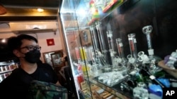 A customer views an array of paraphernalia used to smoke marijuana at the Highland Cafe in Bangkok, Thailand, Thursday, June 9, 2022.