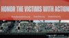FILE - A video display in Seattle reads "Honor the victims with action," and displays the names and websites of anti-gun violence organizations, May 27, 2022, following a moment of silence before a baseball game between the Seattle Mariners and the Housto