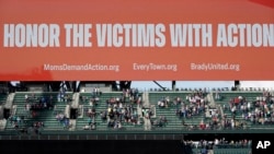 FILE - A video display in Seattle reads "Honor the victims with action," and displays the names and websites of anti-gun violence organizations, May 27, 2022, following a moment of silence before a baseball game between the Seattle Mariners and the Housto