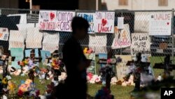 FILE - A woman visits a memorial honoring the victims killed in last week's elementary school shooting in Uvalde, Texas, June 3, 2022.