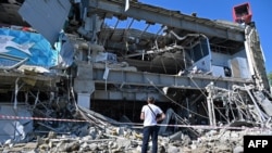Мужчина смотрит на частично разрушенный в результате ракетного обстрела супермаркет на окраине Харькова. 8 июня 2022 года.