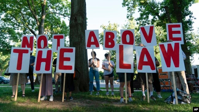 Demonstrators hold signs as they rally before the first Jan. 6, investigation hearing on Capitol Hill in Washington, June 9, 2022.