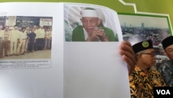Pengelola Ponpes membandingkan foto pendiri Ponpes Abdullah Baraja dengan ketua Khilafatul Muslimin Abdul Qadir Baraja saat ditemui di kompleks Ponpes, Rabu (8/6). (Foto : VOA / Yudha Satriawan)
