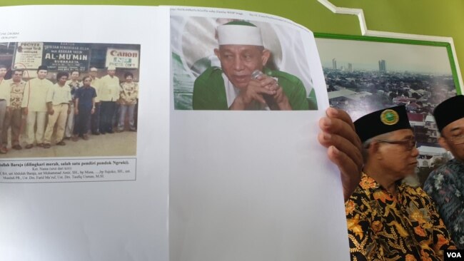 Pengelola Ponpes membandingkan foto pendiri Ponpes Abdullah Baraja dengan ketua Khilafatul Muslimin Abdul Qadir Baraja saat ditemui di kompleks Ponpes, Rabu (8/6). (Foto : VOA / Yudha Satriawan)