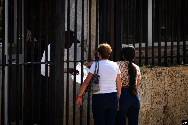 People wait their turns outside the U.S. embassy the day after it reopened its consular services in Havana, Cuba, Wednesday, May 4, 2022. (AP Photo/Ramon Espinosa)