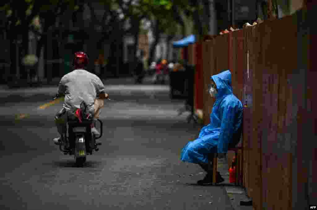 A worker sits next to a fence erected to close a residential area under COVID-19 lockdown in the Huangpu district of Shanghai.