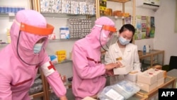 FILE - This picture taken and released from North Korea's official Korean Central News Agency (KCNA) May 31, 2022 shows Korean People's Army medical personnel in protective clothing supplying medicines at a pharmacy in Pyongyang. (Photo by KCNA VIA KNS/AFP)