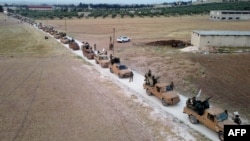 This aerial view shows Turkey-backed Syrian fighters as they arrive to take part in a military exercise in the countryside of the northern city of Manbij, June 2, 2022.