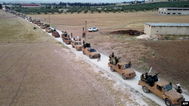This aerial view shows Turkey-backed Syrian fighters as they arrive to take part in a military exercise in the countryside of the northern city of Manbij, June 2, 2022.
