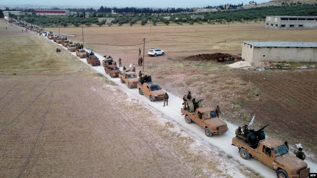 This aerial view shows Turkey-backed Syrian fighters as they arrive to take part in a military exercise in the countryside of the northern city of Manbij, June 2, 2022. 