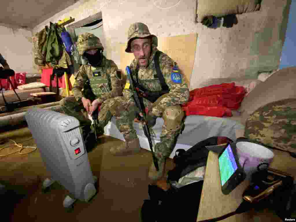 Members of the Ukrainian Territorial Defense Forces watch the FIFA World Cup 2022 qualification playoff semi-final soccer match between Scotland and Ukraine on a mobile phone in a shelter in Kharkiv, Ukraine, June 1, 2022.