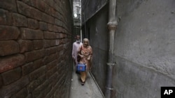 Health workers pass through an alley to give polio vaccines to children in a neighborhood of Lahore, Pakistan, May 23, 2022.
