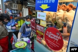 Seorang pedagang menyiapkan sepiring nasi ayam di pusat jajanan di Singapura, 31 Mei 2022. (Foto: Roslan RAHMAN/AFP)