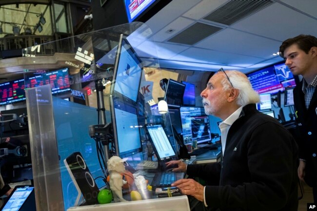 In this photo provided by the New York Stock Exchange, trader Peter Tuchman, seated, works on the floor, June 13, 2022. (Courtney Crow/New York Stock Exchange via AP)