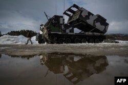 FILE - A soldier walks past a M270 multiple-launch rocket system during the international military exercise Cold Response 22, at Setermoen, in Norway, March 22, 2022.