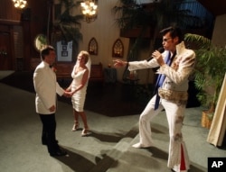 Brian Mills, right, as Elvis marries Richard Johnson and Cheryl Bell of Peoria, Ariz. at the Viva Las Vegas wedding chapel Wednesday, Sept. 9, 2009 in Las Vegas. (AP Photo/Isaac Brekken)