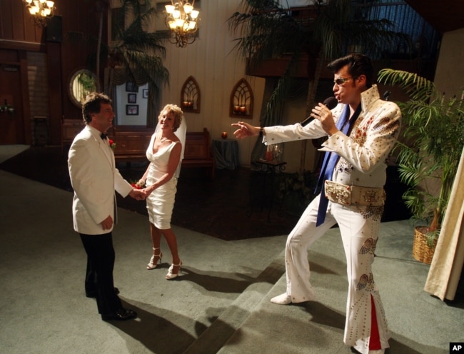 Brian Mills, right, as Elvis marries Richard Johnson and Cheryl Bell of Peoria, Ariz. at the Viva Las Vegas wedding chapel Wednesday, Sept. 9, 2009 in Las Vegas. (AP Photo/Isaac Brekken)