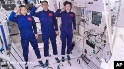 Dans cette capture d'écran capturée au Centre de contrôle aérospatial de Pékin et publiée par l'agence de presse Xinhua, les astronautes chinois de gauche, Liu Yang, Chen Dong et Cai Xuzhe saluent après être entrés dans le module central de la station spatiale Tianhe, le 5 juin 2022.