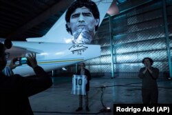 Seorang pria berpose di sebelah pesawat yang didedikasikan untuk mendiang legenda sepak bola Diego Maradona. (Foto: AP)