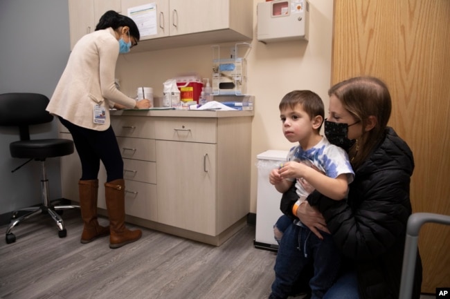 FILE - Ilana Diener holds her son, Hudson, 3, during an appointment for a Moderna COVID-19 vaccine trial in Commack, N.Y. on Nov. 30, 2021. (AP Photo/Emma H. Tobin, File)