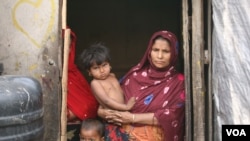 FILE - Rohingya refugee Jomila Begum stands with two of her eight children, at her shack inside a Rohingya refugee colony in Jammu city, north India, April12, 2022. Jomila’s husband was picked up by Indian police and sent to jail, recently, after being ch