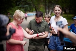 볼로디미르 젤렌스키(가운데) 우크라이나 대통령이 5일 자포리자 방문 도중, 팔에 사인해달라는 시민 요청에 응하고 있다.