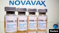 FILE PHOTO: Vials with a sticker reading, "COVID-19 / Coronavirus vaccine / Injection only" and a medical syringe are seen in front of a displayed Novavax logo on Oct. 31, 2020. 