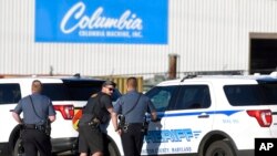Police stand near where a man opened fire at a business, killing three people before the suspect and a state trooper were later wounded in a shootout, according to authorities, in Smithsburg, Md., June 9, 2022.