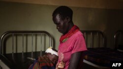 Une femme séjourne avec un enfant souffrant de malnutrition à l'hôpital de Kaabong à Kaabong, dans la région de Karamoja, en Ouganda, le 25 mai 2022.