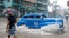 Un auto de alquiler de fabricación estadounidense transita una calle de La Habana, inundada por las fuertes lluvias del 3 de junio de 2022.
