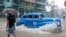 Un auto de alquiler de fabricación estadounidense transita una calle de La Habana, inundada por las fuertes lluvias del 3 de junio de 2022.