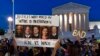 FILE - A demonstrator holds up a a sign with pictures of Supreme Court Justices Clarence Thomas, Brett Kavanaugh, Samuel Alito, Amy Coney Barrett, and Neil Gorsuch, as people protest outside of the U.S. Supreme Court, May 3, 2022.