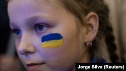 Дівчина з намальованим на обличчі українським прапором відвідує культурну подію на підтримку України. Дніпро, 14 травня 2022