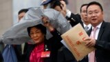 A female delegate uses a plastic cover to shield from the rain as she leaves the Great Hall of the People with others after attending the opening ceremony of the 19th Party Congress in Beijing, Oct. 18, 2017. 