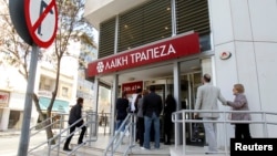 Depositors wait to enter a branch of Laiki Bank in Nicosia, March 29, 2013. 