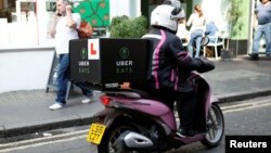 An UberEATS food delivery courier rides her scooter in London on September 7, 2016. 