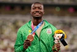 Le médaillé de bronze Hugues Zango, du Burkina Faso, pose lors de la cérémonie de remise des médailles du triple saut masculin aux Jeux olympiques d'été de 2020, jeudi 5 août 2021, à Tokyo.