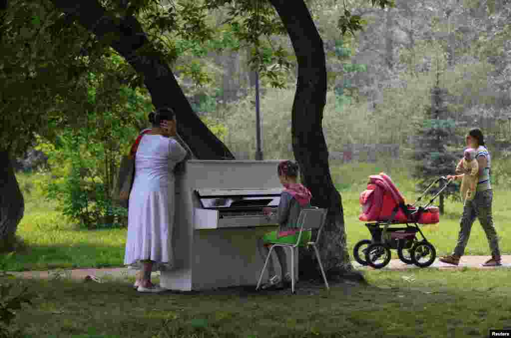 A girl plays a piano in the park in Russia&#39;s Siberian city of Krasnoyarsk. A group of young enthusiasts bought an old Soviet-made piano, adjusted it, painted white and placed in a park for free use by all visitors. 