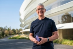 CEO Apple Tim Cook memegang iPhone 12 dengan warna ungu baru, dalam gambar diam ini dari video utama acara khusus di Apple Park di Cupertino, California, AS yang dirilis pada 20 April 2021. (Foto: APPLE INC/Reuters)