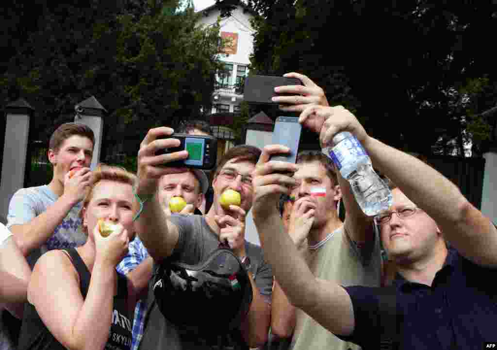 Lithuanians take "selfies" as they eat Polish apples in front of the Russian Embassy in Vilnius. They are showing support for Poland after Russia restricted apple imports from Poland.